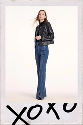 a lady in black leather jacket with blue flared jeans